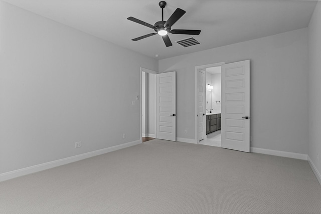 unfurnished bedroom with light colored carpet, baseboards, visible vents, and ensuite bath