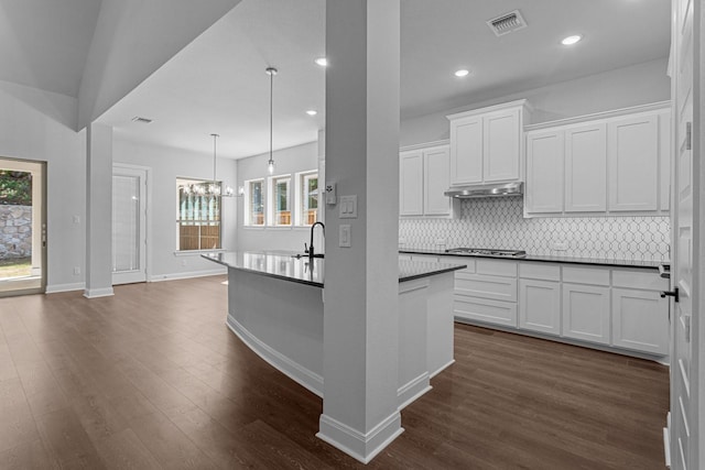 kitchen with decorative backsplash, dark countertops, visible vents, and a wealth of natural light