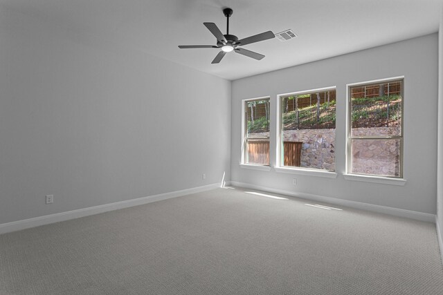 empty room featuring visible vents, ceiling fan, carpet floors, and baseboards