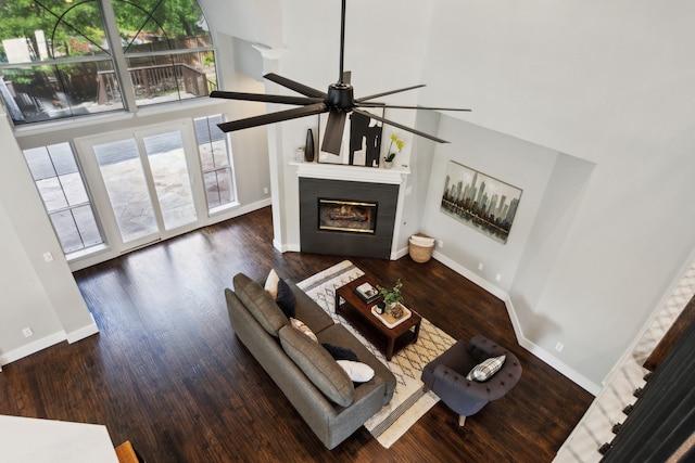 living area featuring a wealth of natural light, a ceiling fan, a glass covered fireplace, and a high ceiling
