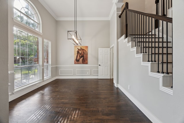 unfurnished dining area featuring stairway, ornamental molding, wood finished floors, and a towering ceiling