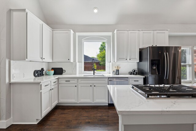 kitchen featuring white cabinets, light stone counters, a sink, appliances with stainless steel finishes, and dark wood-style flooring