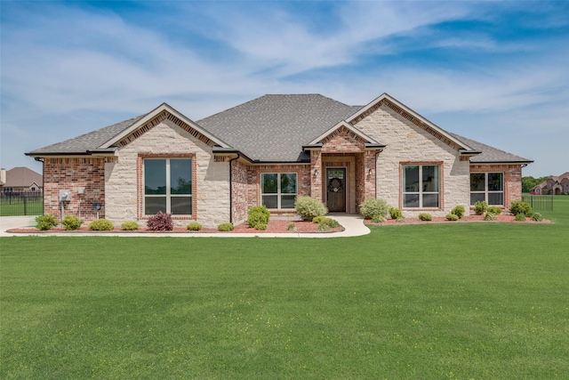 view of front of property with brick siding, a shingled roof, fence, and a front lawn