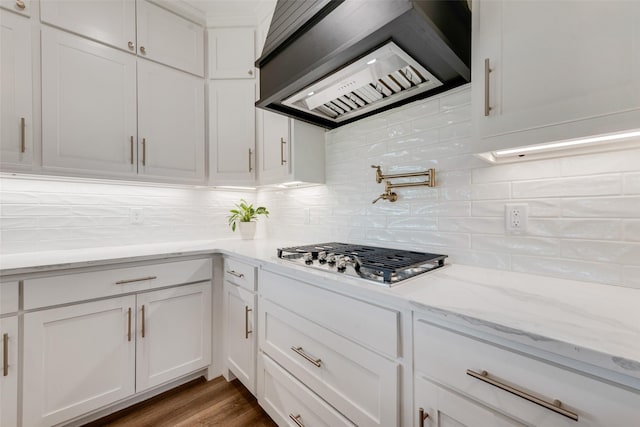 kitchen featuring white cabinets, premium range hood, decorative backsplash, stainless steel gas cooktop, and light stone counters