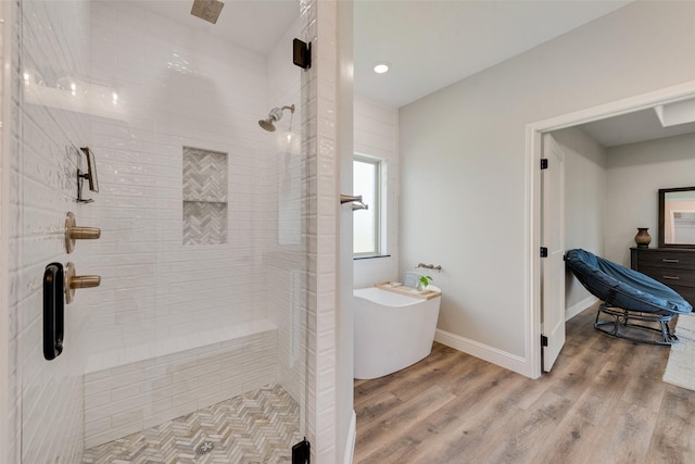 full bathroom featuring a freestanding bath, baseboards, a stall shower, and wood finished floors