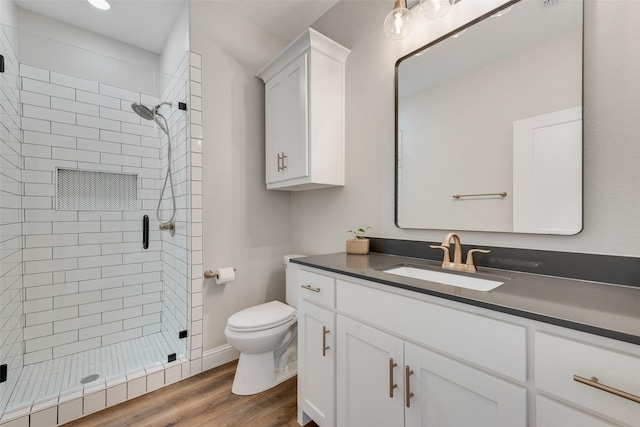 bathroom with a shower stall, wood finished floors, vanity, and toilet