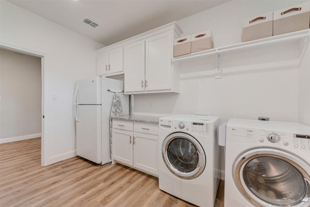 laundry area with light wood-type flooring, baseboards, visible vents, cabinet space, and washer and dryer