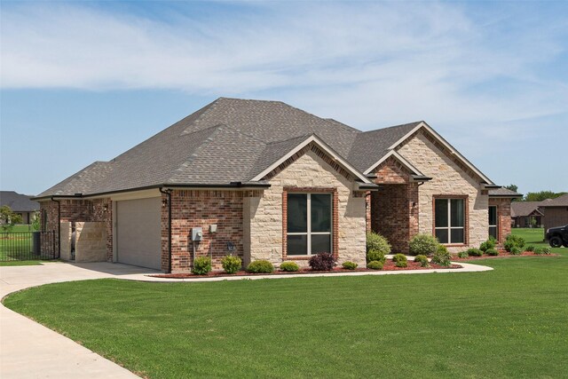 view of front of home featuring a garage, roof with shingles, a front yard, stone siding, and concrete driveway