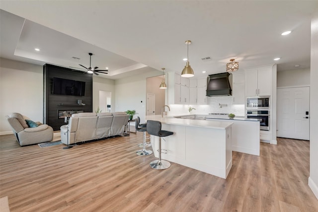 kitchen featuring recessed lighting, premium range hood, backsplash, built in microwave, and oven