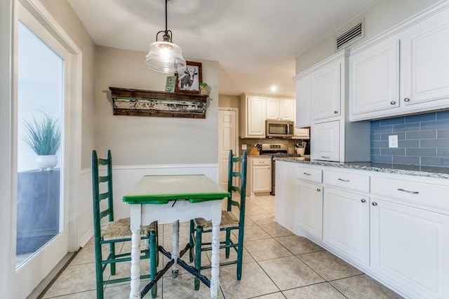 kitchen with hanging light fixtures, white cabinets, visible vents, appliances with stainless steel finishes, and tasteful backsplash