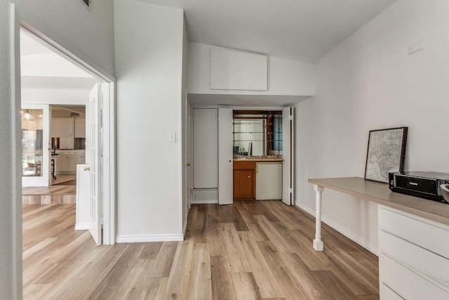 interior space with white cabinets, dishwasher, light wood-type flooring, and baseboards