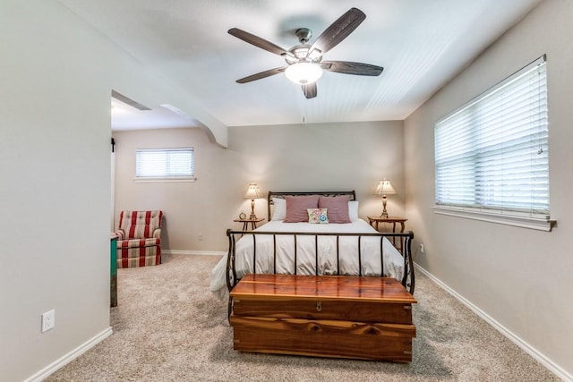 carpeted bedroom with arched walkways and baseboards