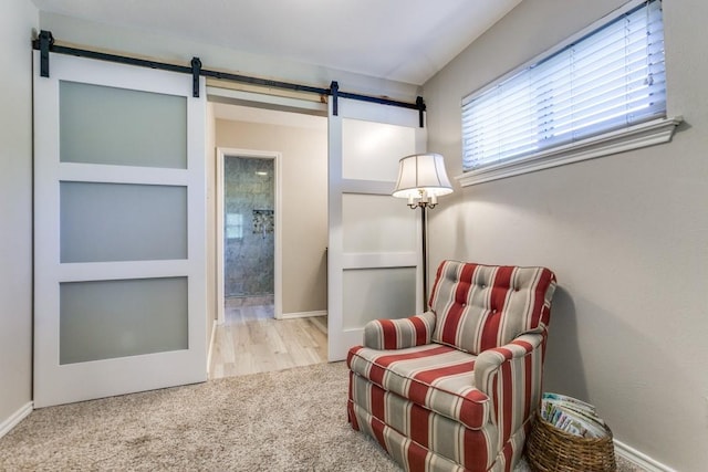 living area featuring carpet flooring, a barn door, and baseboards