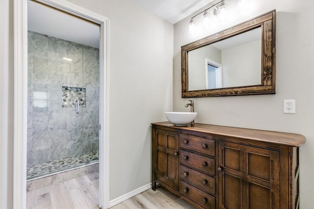 bathroom featuring a stall shower, vanity, baseboards, and wood finished floors