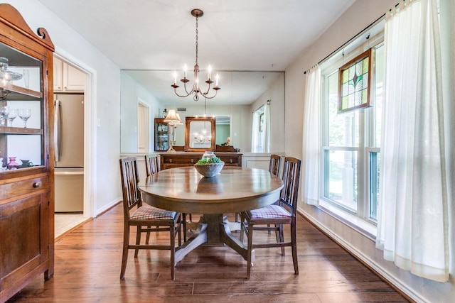 dining area featuring baseboards, a healthy amount of sunlight, a chandelier, and wood finished floors