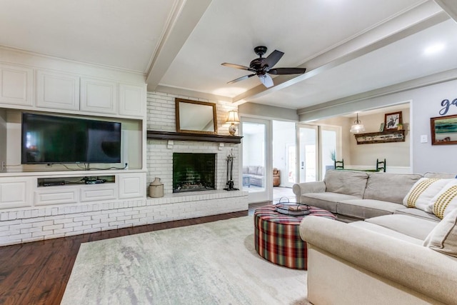 living room with wood finished floors, a ceiling fan, beamed ceiling, and a fireplace