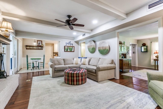 living area with a ceiling fan, visible vents, beam ceiling, and dark wood-type flooring
