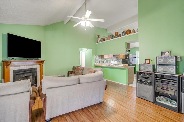 10125 Leatherwood Dr, Fort Worth, TX 76108 - living area featuring ceiling fan, high vaulted ceiling, a tile fireplace, light wood finished floors, and beam ceiling
