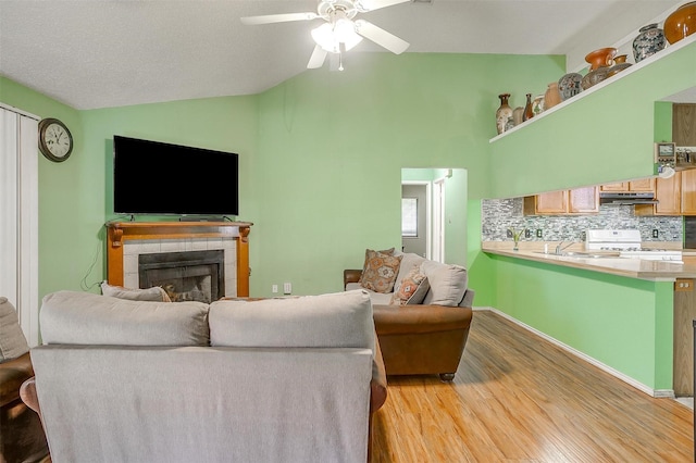 10125 Leatherwood Dr, Fort Worth, TX 76108 - living room featuring a tiled fireplace, ceiling fan, light wood-style floors, and lofted ceiling