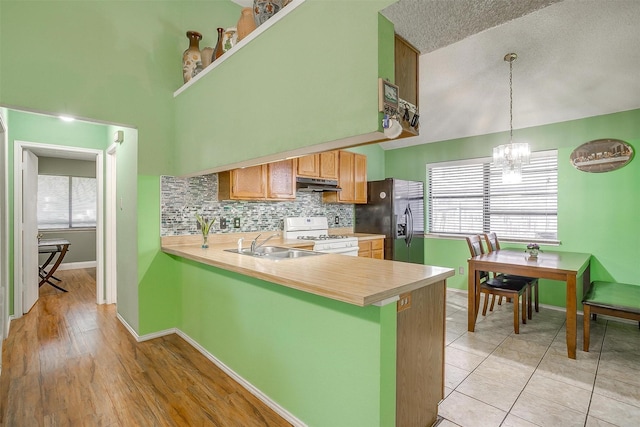 10125 Leatherwood Dr, Fort Worth, TX 76108 - kitchen with light countertops, white range with gas stovetop, under cabinet range hood, and black refrigerator with ice dispenser