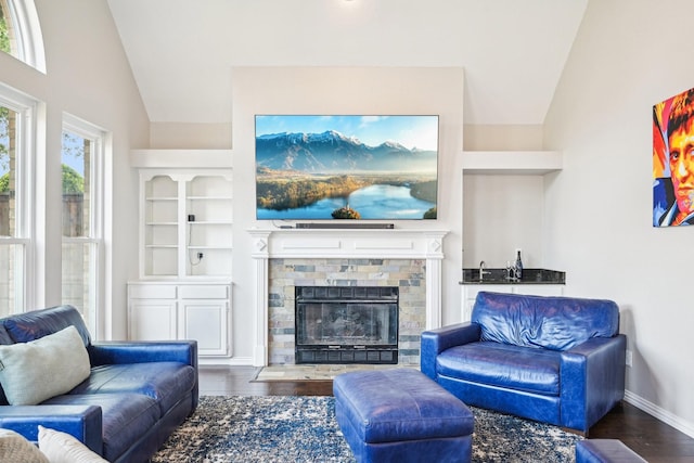 living room featuring baseboards, wood finished floors, a fireplace, and lofted ceiling