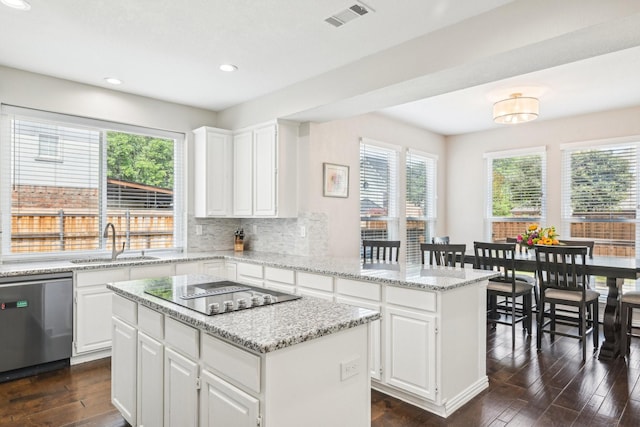 kitchen featuring a sink, black electric stovetop, a center island, visible vents, and dishwasher
