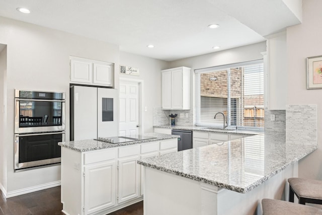 7812 Alderwood Pl, Plano, TX 75025 - kitchen with appliances with stainless steel finishes, a sink, a peninsula, backsplash, and white cabinetry