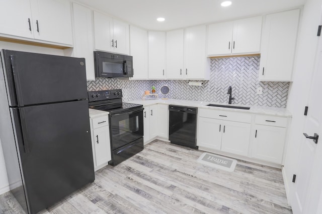 kitchen with a sink, white cabinetry, and black appliances