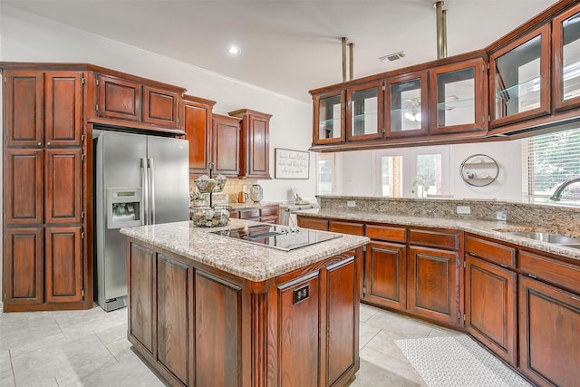 kitchen with black electric cooktop, a center island, a sink, visible vents, and stainless steel fridge with ice dispenser