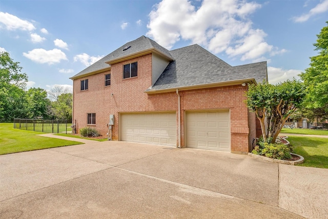 view of property exterior featuring brick siding, a yard, driveway, and fence