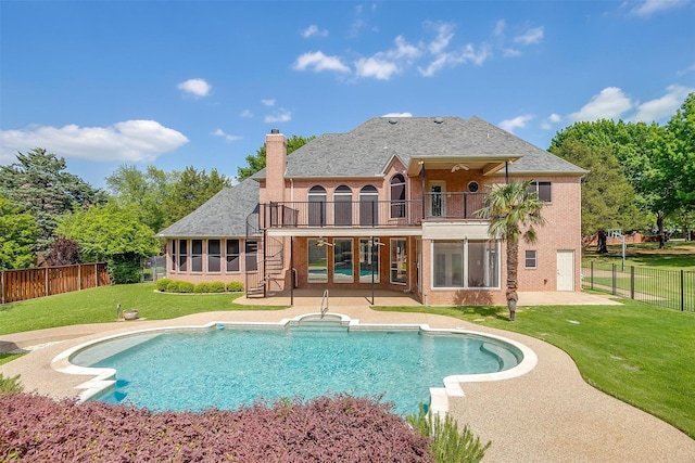 back of house with a chimney, a balcony, a patio, a lawn, and a sunroom