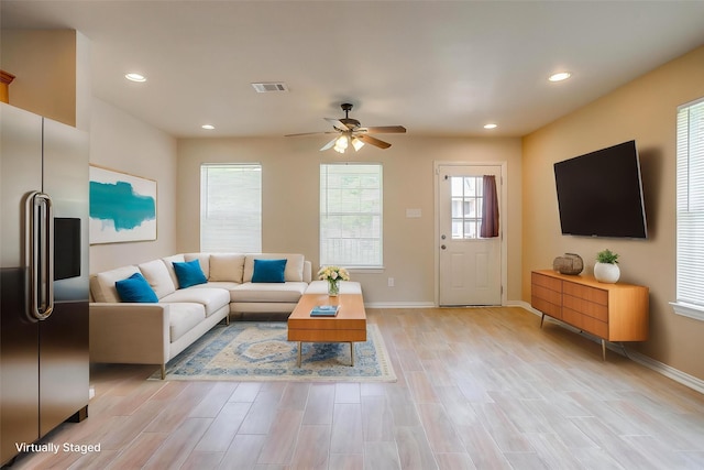 living room with light wood finished floors, baseboards, and ceiling fan
