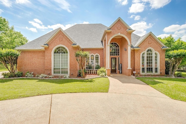 ranch-style house with brick siding, roof with shingles, and a front yard
