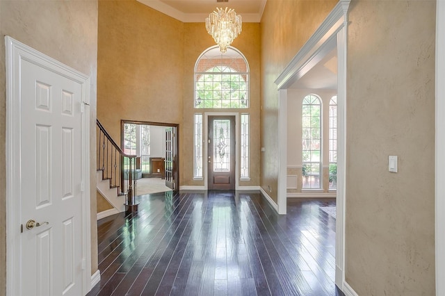 entrance foyer with dark wood-type flooring, a chandelier, baseboards, and stairs