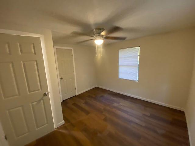 unfurnished bedroom with dark wood-type flooring, baseboards, and a ceiling fan
