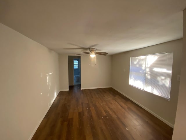 empty room with dark wood-style flooring, baseboards, and ceiling fan