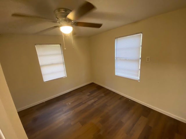 unfurnished room with dark wood-style flooring, baseboards, and a ceiling fan