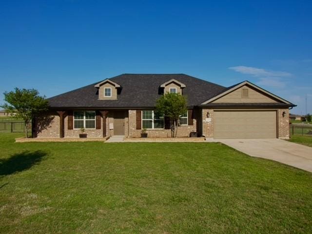 view of front of home with a front yard, brick siding, a garage, and driveway