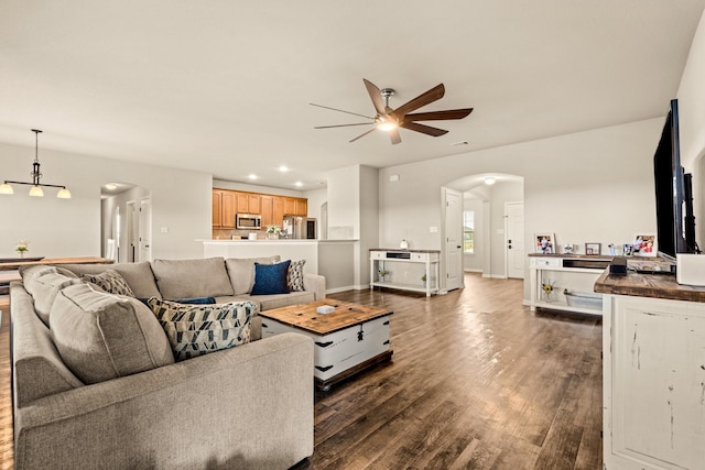 living room featuring dark wood-type flooring, arched walkways, ceiling fan, and recessed lighting
