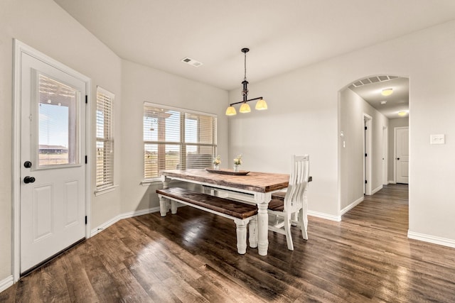 dining room with baseboards, a chandelier, visible vents, arched walkways, and wood finished floors