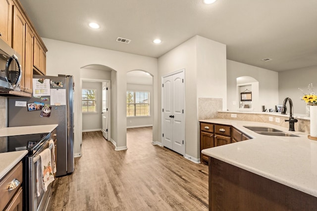 kitchen with visible vents, arched walkways, a sink, light countertops, and stainless steel appliances