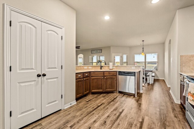 kitchen featuring appliances with stainless steel finishes, wood finished floors, light countertops, a sink, and baseboards