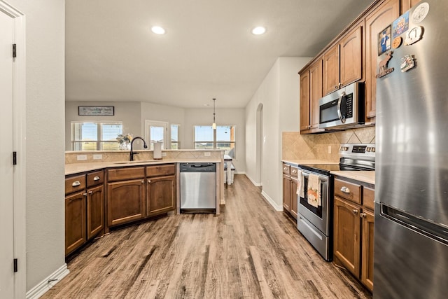 kitchen featuring light wood-style flooring, a sink, light countertops, and stainless steel appliances