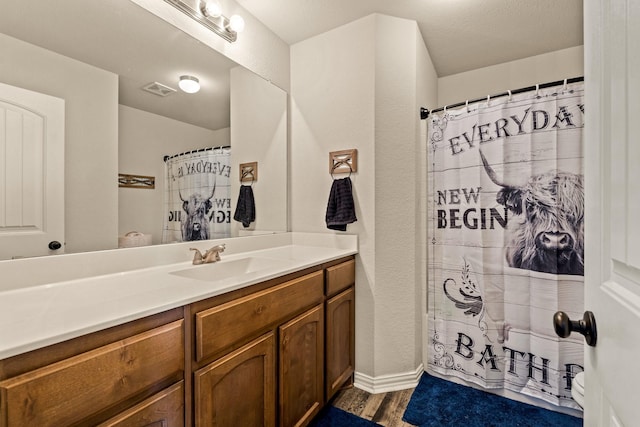 bathroom featuring wood finished floors, vanity, a shower with shower curtain, and visible vents