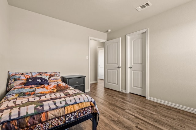 bedroom featuring wood finished floors, baseboards, and visible vents