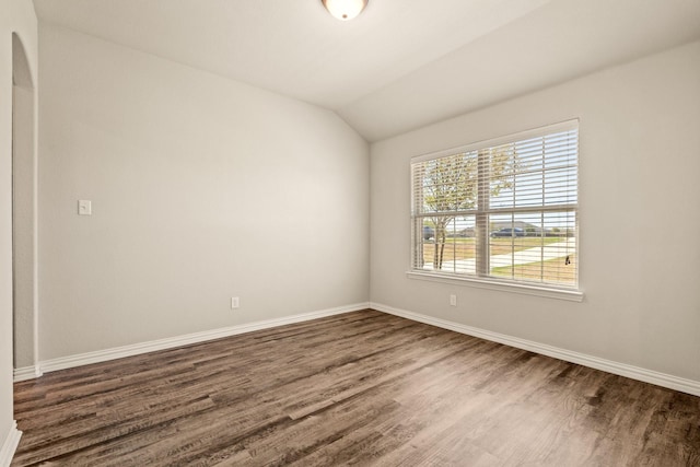 empty room featuring baseboards, vaulted ceiling, and wood finished floors