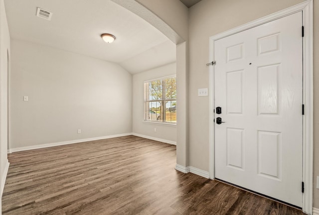 entrance foyer with baseboards, visible vents, lofted ceiling, arched walkways, and wood finished floors