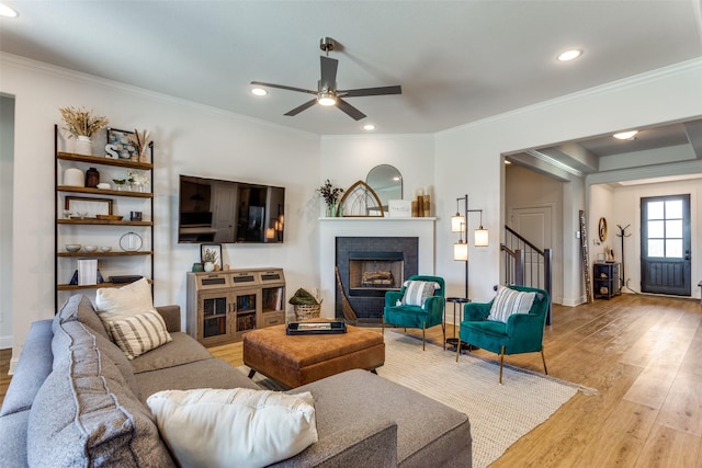 living room with a ceiling fan, light wood-type flooring, a fireplace, stairway, and recessed lighting