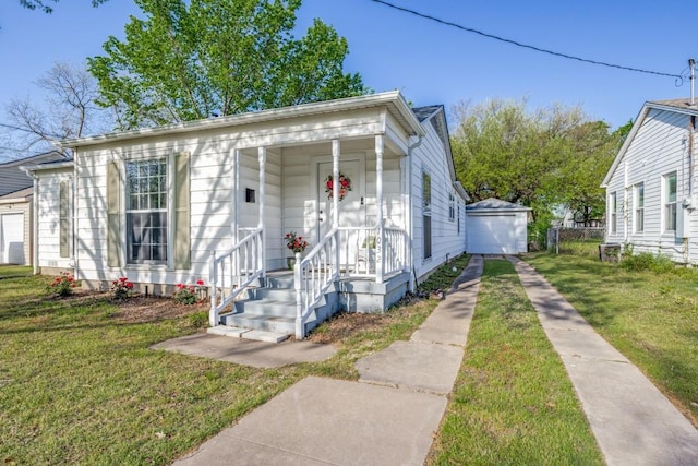 view of front facade with an outdoor structure, driveway, a front yard, and a detached garage