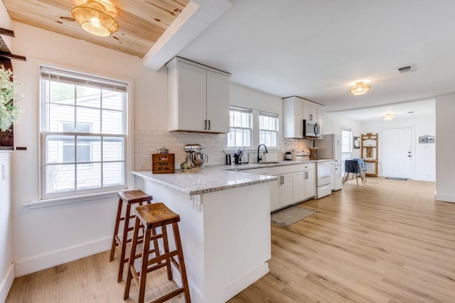 kitchen with decorative backsplash, baseboards, white electric range, a sink, and light wood finished floors